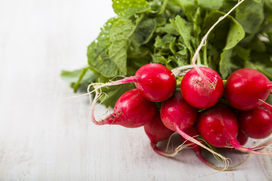 Ripe red radish with leaves on a wooden table close-up. Fresh ve