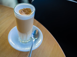 Latte coffee in tall glass on cafe table