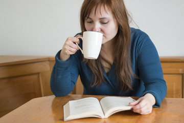 Girl drinking coffee and reading a book