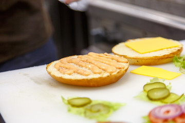 The cook prepares the hamburgers in the kitchen. Bun, veggies, P