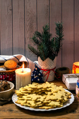 Plate with tasty Christmas cookies, candle and gift on wooden table.