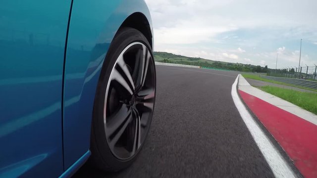 CLOSE UP: Turquoise sportscar driving very fast on twisty racetrack circuit