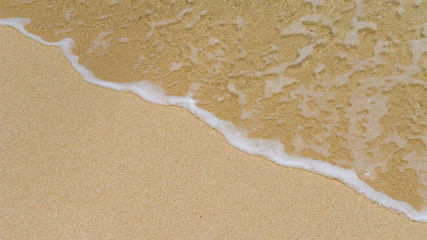 Fototapeta na wymiar Yellow Sand and Gentle Wave Rolling with some Foam