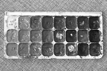  Watercolor paints box on fabric background. Used paint palette. Black and white