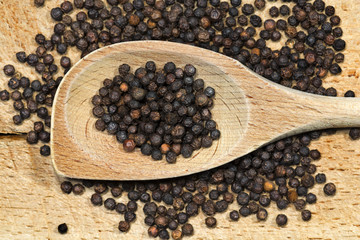 Peppercorns on a wooden spoon and cutting board