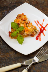 Casserole with chicken and pumpkin on a white square plate. old rustic background. Top view. Close-up
