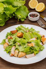 Salad of smoked chicken, croutons, lettuce and parmesan. Wooden rustic background. Top view. Close-up