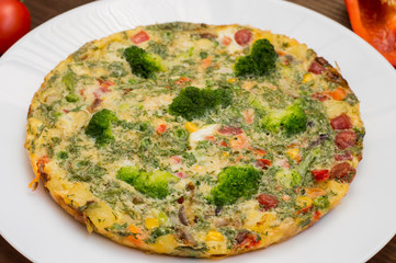 Spanish tortilla on a white plate. Restaurant supply. Wooden rustic table. Top view