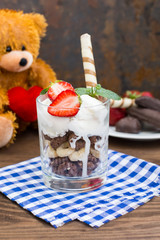 Ice cream with strawberries, mint and muesli. Wooden rustic table.