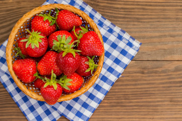 Strawberries in the basket on wooden background. Top view. Close-up