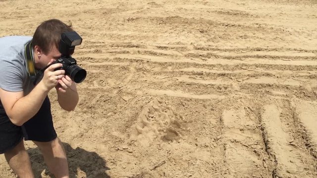 Photographer in motion. Young handsome photographer upholds his camera while shooting.