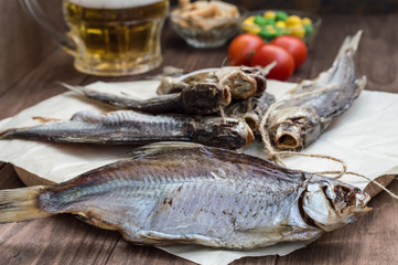 Dried fish, roach with a glass of cold beer on  wooden table. Top view. Close-up