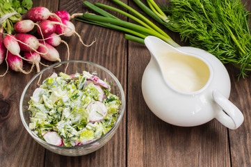 Salad with radishes, lettuce, spinach and sour cream on a wooden table. Close-up