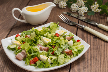 Salad with spinach, quail eggs and bacon. Wooden table. Top view. Close-up