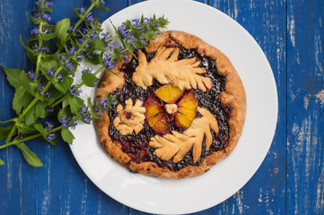 Cake with currant jam and slice of orange on a wooden background. Homemade baking. Top view. Close-up
