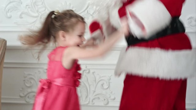 Santa and pretty little girl having fun and dancing
