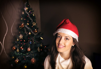 A cute girl with Santa's hat in front of a Christmas tree