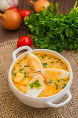 Cream soup with smoked chicken and eggs on a wooden table. Top view. Close-up