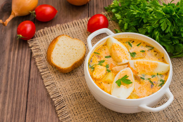 Cream soup with smoked chicken and eggs on a wooden table. Top view. Close-up