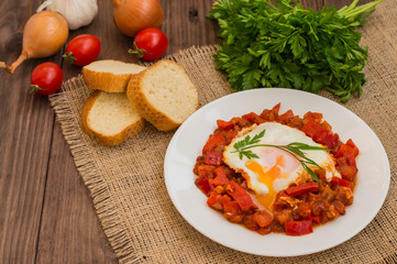 Shakshuka on a white plate. Traditional Jewish dish. Wooden table. Top view. Close-up