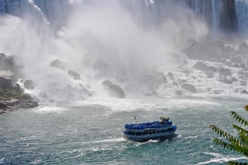 Fototapeta premium Touristen in blauen Regenwesten im Schiff an den Niagara Wasserfällen: American Falls, Bridal Veil Falls in Ontario, Kanada 