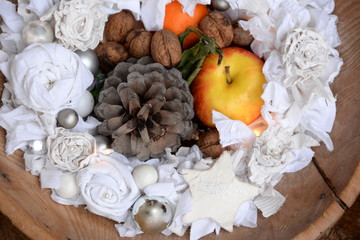 Weihnachtstraum, alte Holzschüssel mit weihnachtlichen weißen Stoffblumenkranz, dekoriert mit Christbaumkugeln, Stern, Pinienzapfen, Apfel, Mandarine und Walnüssen