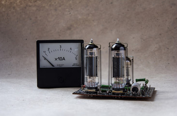 composition of tube amplifier and vintage ammeter. electronic background.