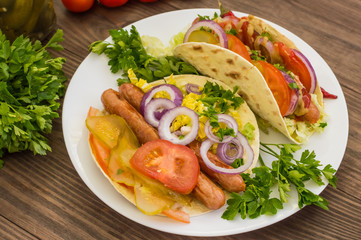 Ingredients for a picnic consisting of vegetables and sausages grilled on wooden rustic background, top view. Close-up