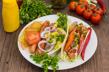 Ingredients for a picnic consisting of vegetables and sausages grilled on wooden rustic background, top view. Close-up