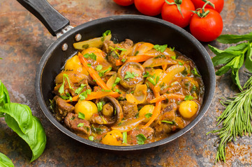 Meat in Burgundy in a frying pan. Top view. Old table. Close-up
