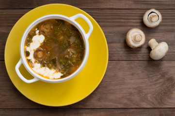 Green borscht with mushrooms. Wooden background. Top view