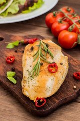 Chicken fillet, fried on the grill and laid out  a wooden board with spices  herbs.  table. Top view