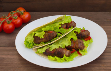 Tortilla with meat wrapped in bacon and herbs. Wooden background