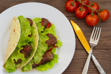 Tortilla with meat wrapped in bacon and herbs. Wooden background