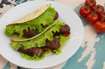 Tortilla with meat wrapped in bacon and herbs. Wooden background. Top view. Close-up