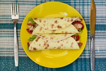 Tortilla with chicken, croutons, mozzarella, tomatoes, bell peppers, sauce and greens. Top view. Close-up
