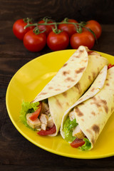 Tortilla with chicken, croutons, mozzarella, tomatoes, bell peppers, sauce and greens. Top view. Close-up