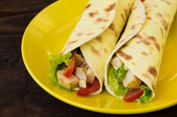 Tortilla with chicken, croutons, mozzarella, tomatoes, bell peppers, sauce and greens. Top view. Close-up
