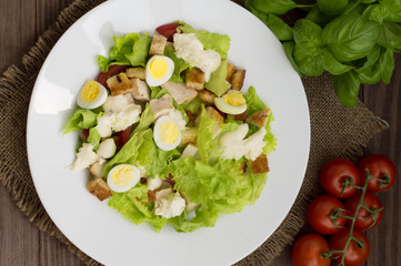 Salad with radishes, arugula, chicken and quail egg on a wooden background, top view