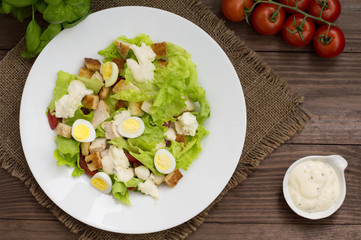 Salad with radishes, arugula, chicken and quail egg on a wooden background, top view