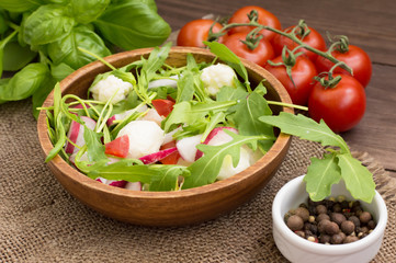 Salad with radish and arugula on a wooden background. Top view. Close-up