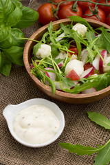 Salad with radish and arugula on a wooden background. Top view. Close-up