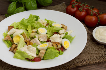 Salad with radishes, arugula, chicken and quail egg on a wooden background, top view