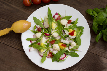 Salad with radishes, arugula, chicken and quail egg on a wooden background, top view