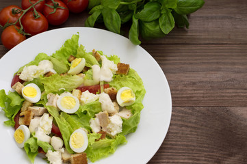Salad with grilled chicken, lettuce and mozzarella cheese on a wooden background. Top view. Close-up