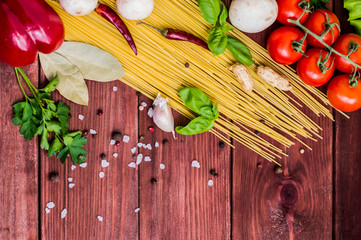 Dry pasta with tomatoes, herbs and spices for tomato sauce, on wooden background, top view