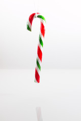 Candy cane held vertically by a string against a white background