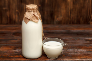 Bottle of milk and cup on rustic wooden table