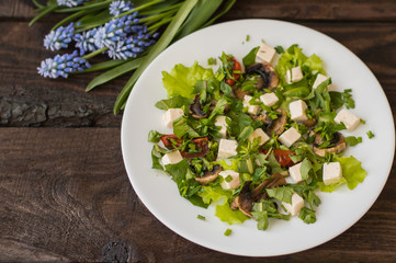 Salad with mushrooms, grilled tomatoes  herbs and feta cheese. Wooden background. Top view