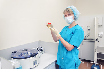 the nurse at the clinic with a sterile plastic jar for taking tests. The procedural is a table and a centrifuge
